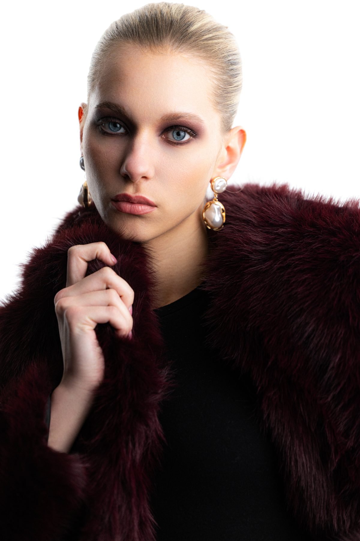 Editorial shot in a burgundy fur coat, white studio backdrop